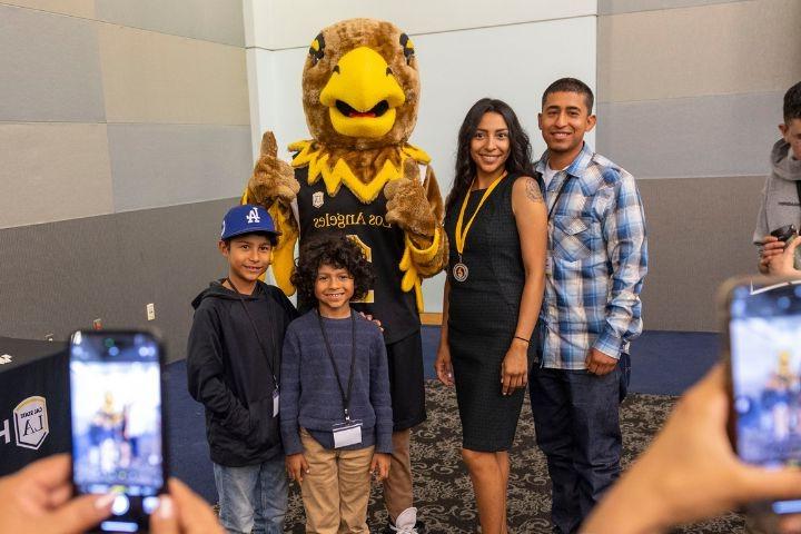 Family of four with Eddie Eagle standing while taking a photo